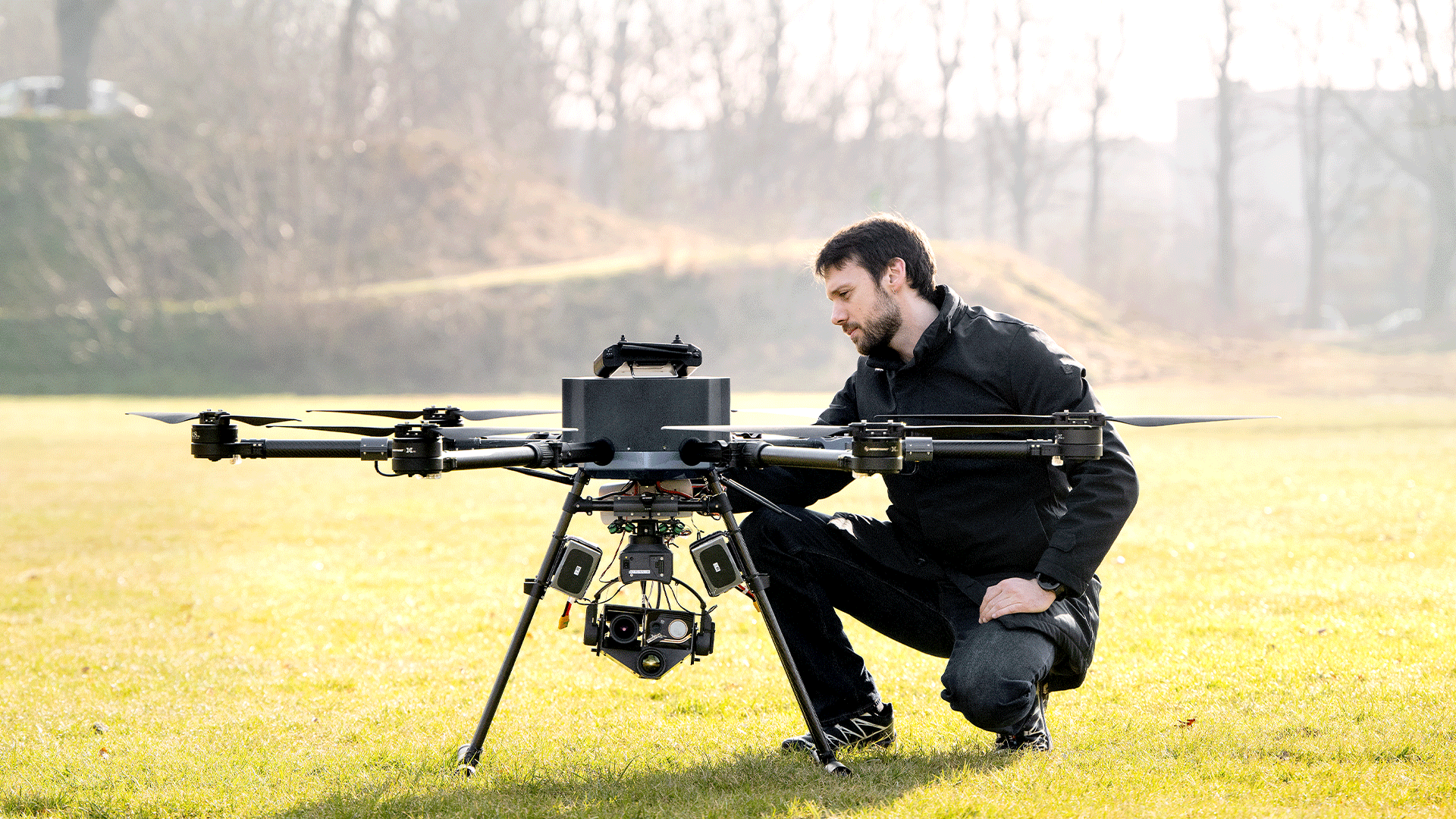 Man inspecting a large drone that is sitting on a lawn. Foto: Bax Lindhardt